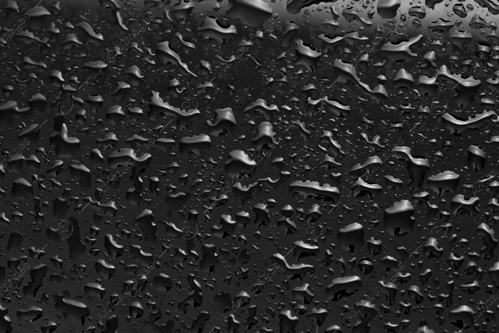 Photo of Water drops on dark grey glass surface, top view