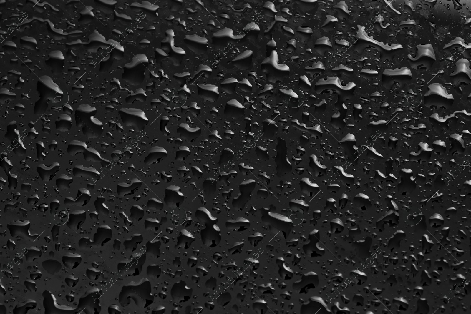 Photo of Water drops on dark grey glass surface, top view