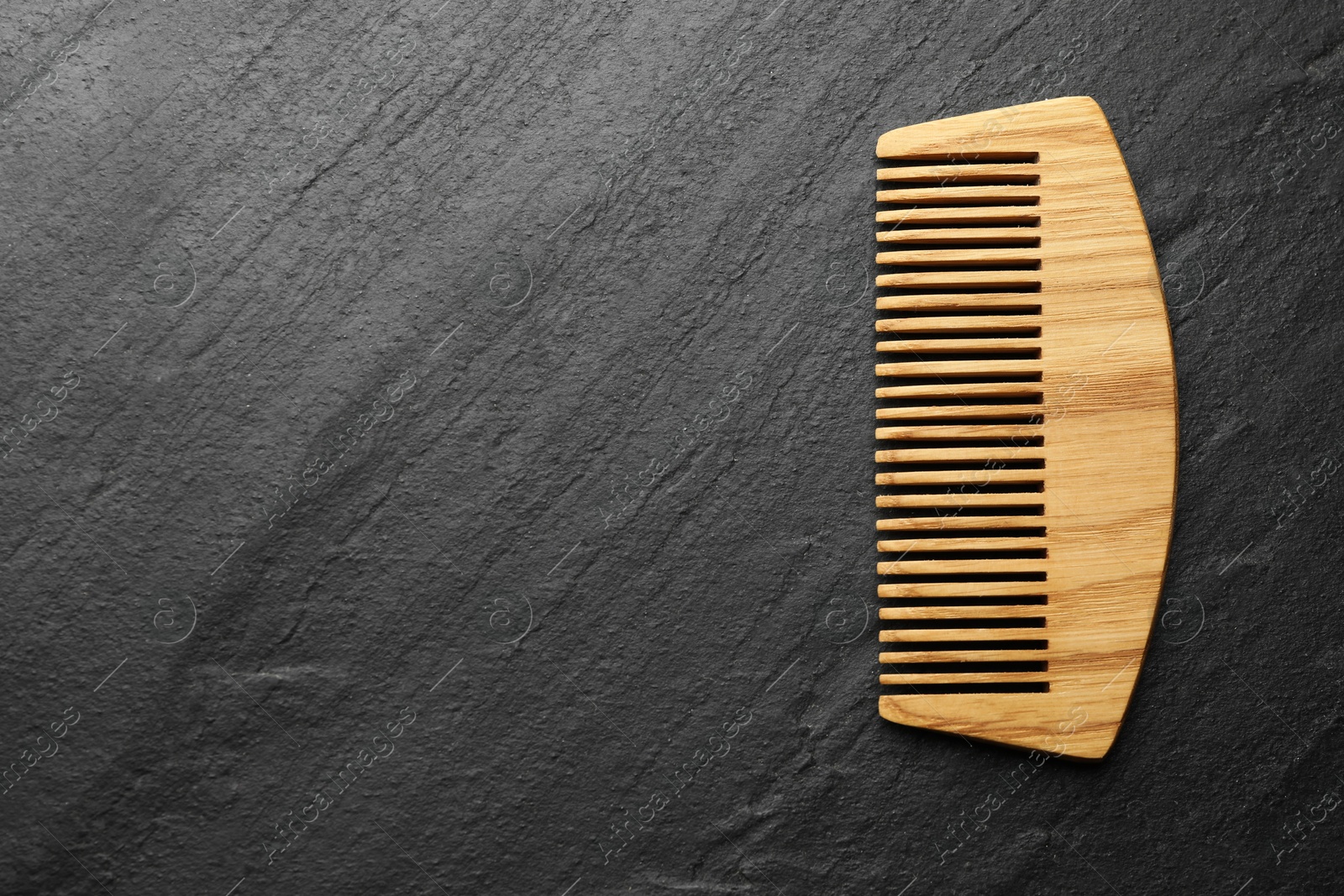 Photo of One wooden hair comb on grey background, top view. Space for text