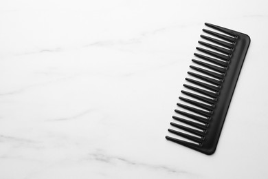 Photo of One black plastic comb on white marble table, top view. Space for text