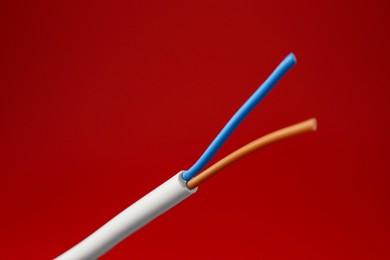 Photo of Stripped electrical wire on red background, closeup