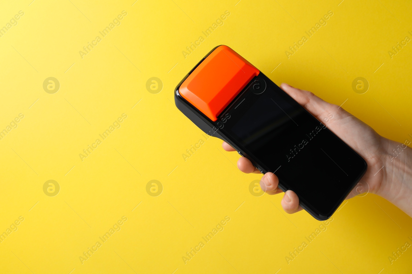 Photo of Woman with payment terminal on yellow background, closeup. Space for text