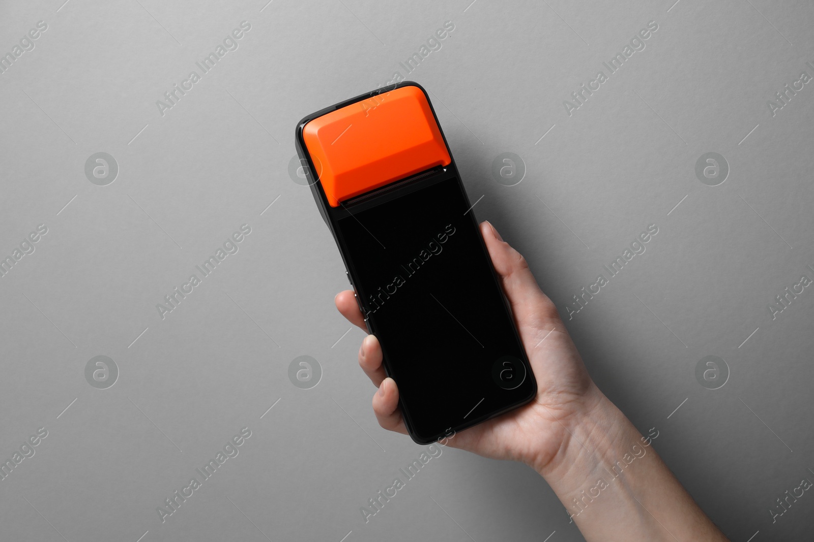 Photo of Woman with payment terminal on grey background, closeup. Space for text