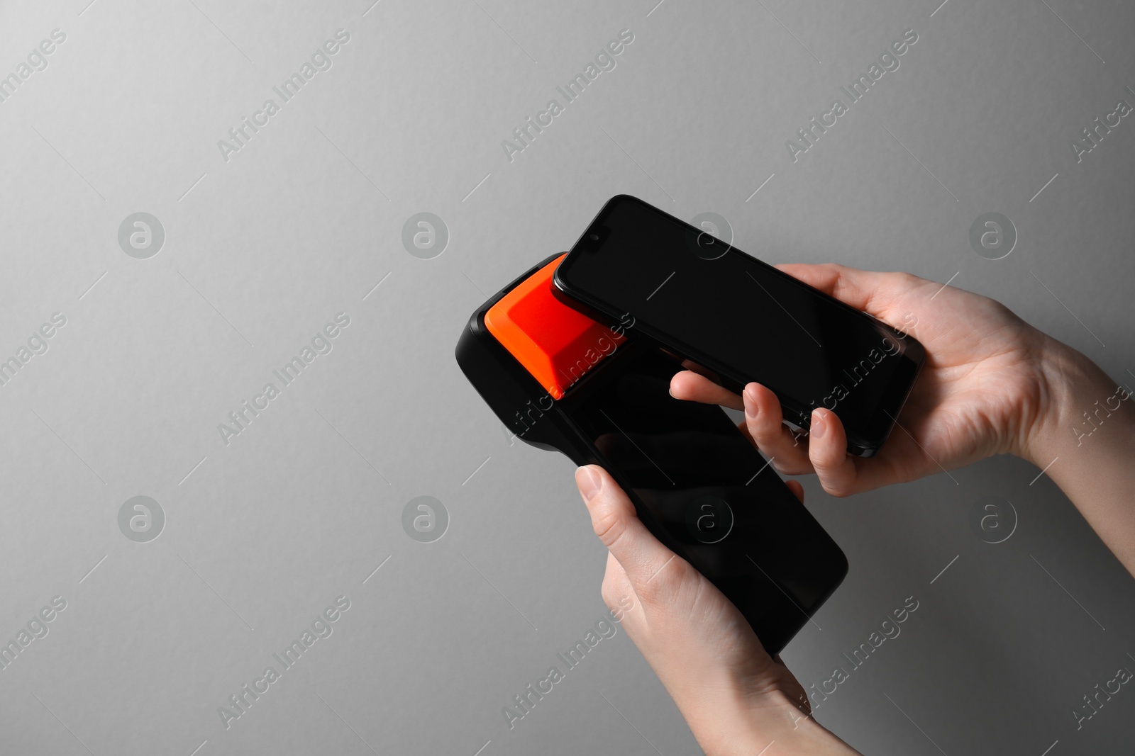 Photo of Woman with smartphone using payment terminal on grey background, closeup. Space for text