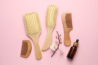 Photo of Wooden hair brushes, combs, cosmetic product and orchid branch on pink background, flat lay