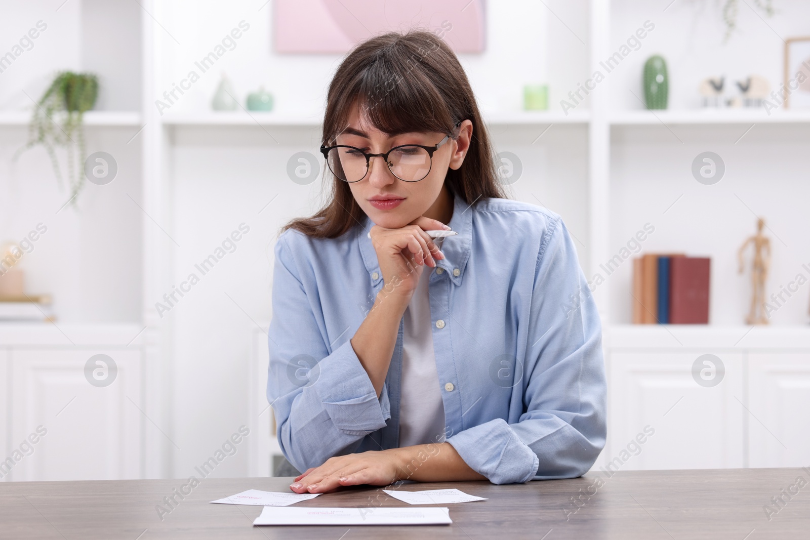 Photo of Paying bills. Woman with different invoices at wooden table indoors