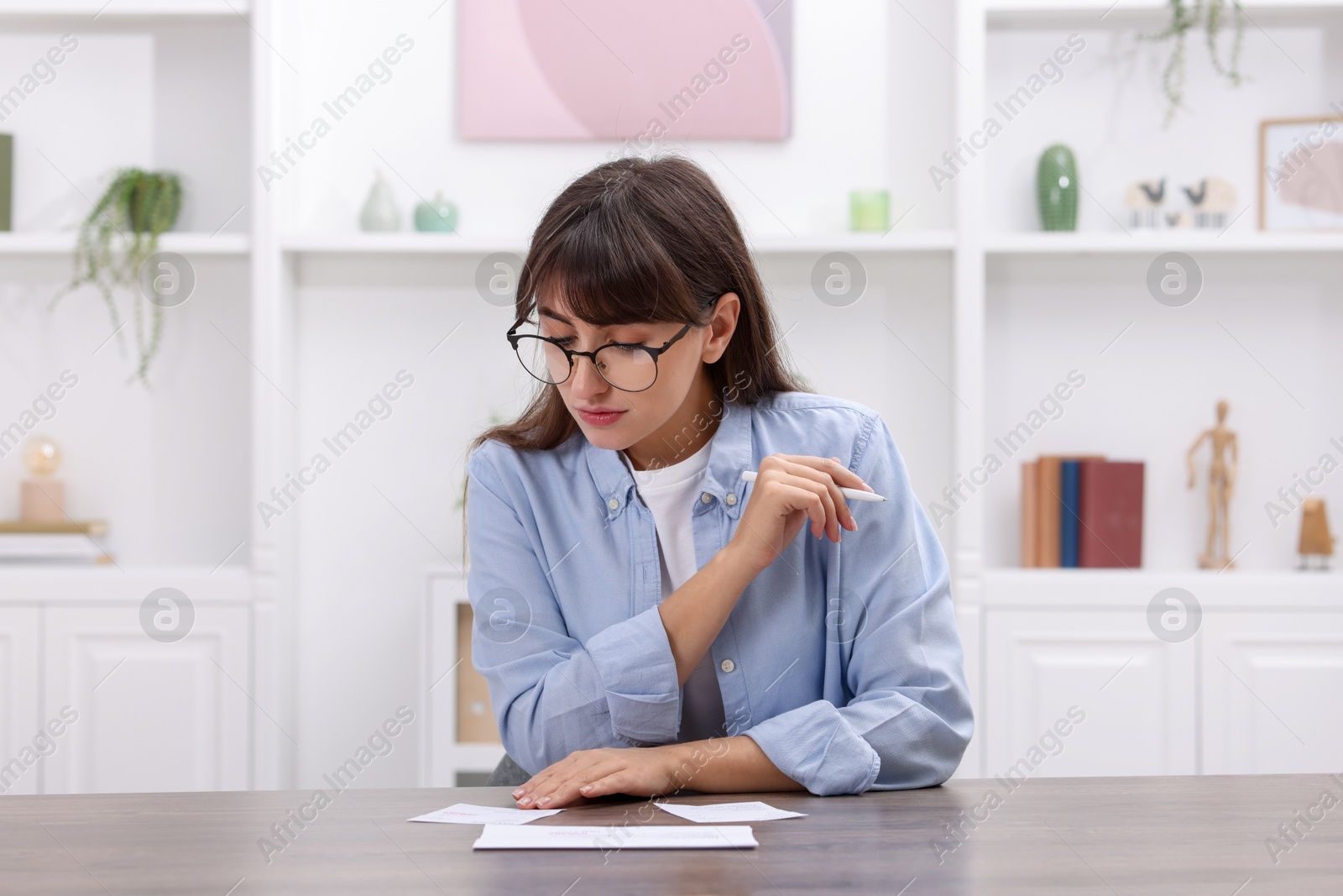 Photo of Paying bills. Woman with different invoices at wooden table indoors