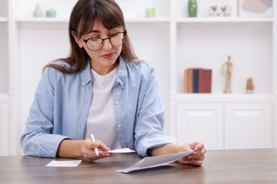 Photo of Paying bills. Woman with different invoices at wooden table indoors, space for text