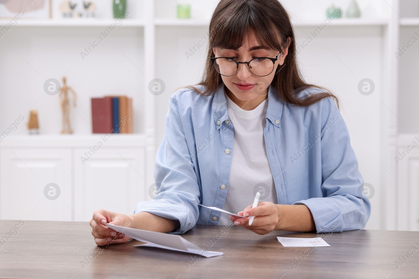 Photo of Paying bills. Woman with different invoices at wooden table indoors, space for text