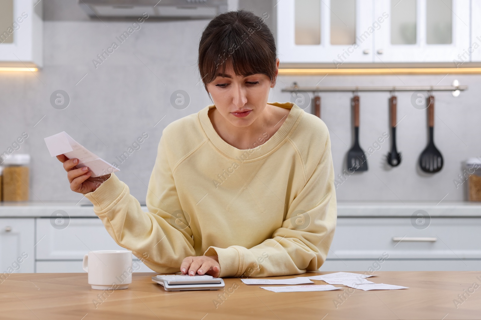 Photo of Paying bills. Woman with different invoices and calculator at wooden table indoors