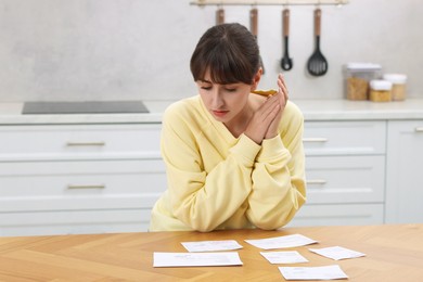 Photo of Paying bills. Woman with different invoices at wooden table indoors