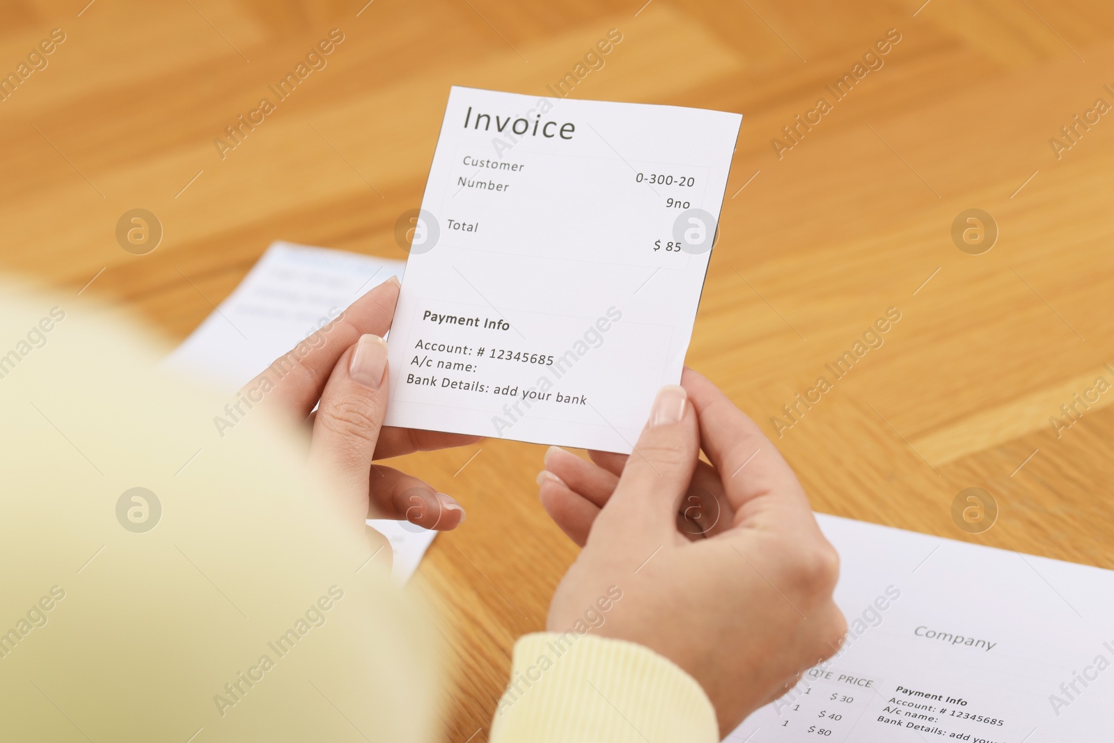 Photo of Paying bills. Woman with different invoices at wooden table indoors, closeup