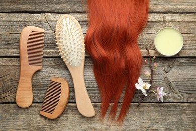 Photo of Brush, combs, wax and lock of hair on wooden table, flat lay