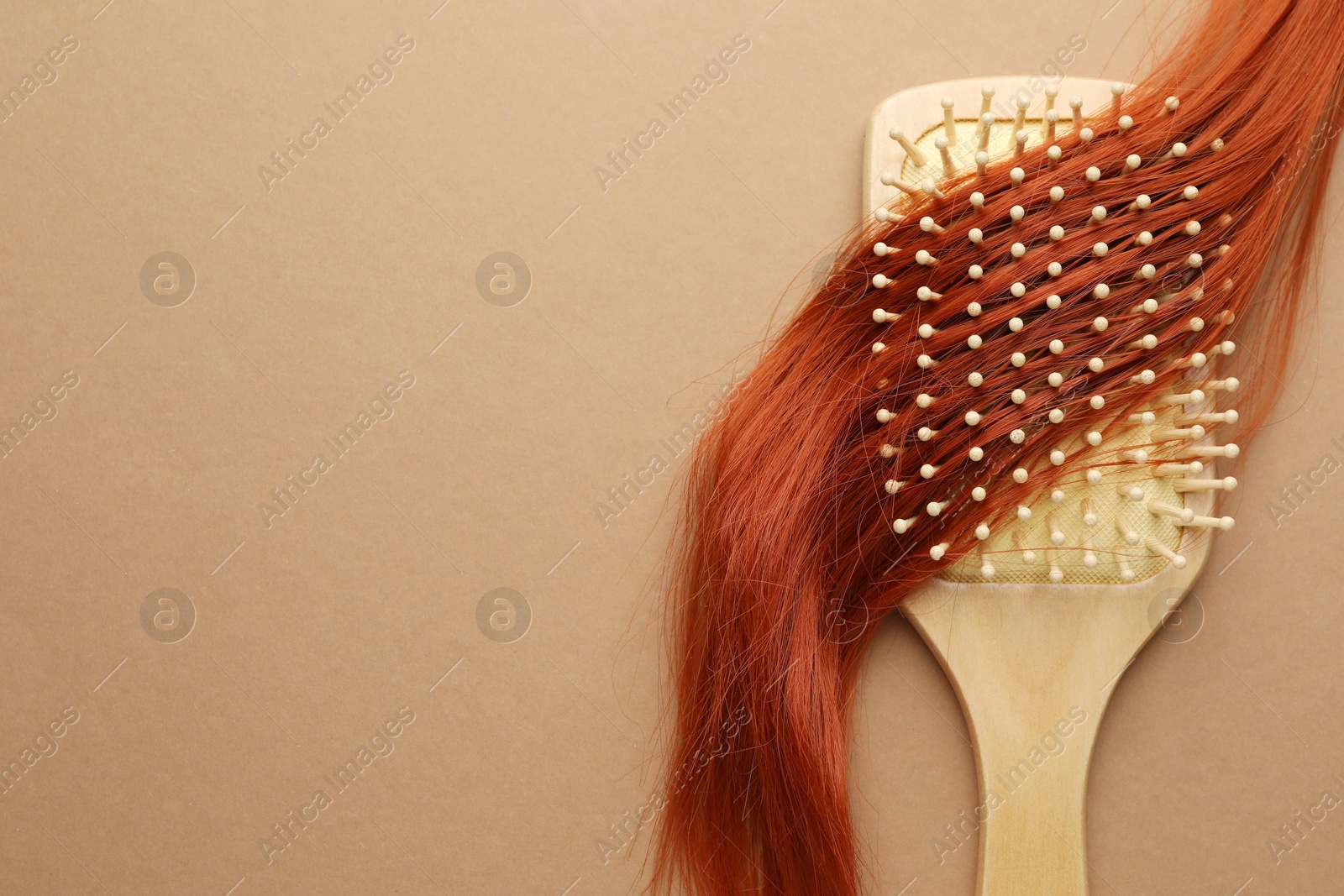 Photo of Wooden brush and lock of hair on beige background, top view. Space for text