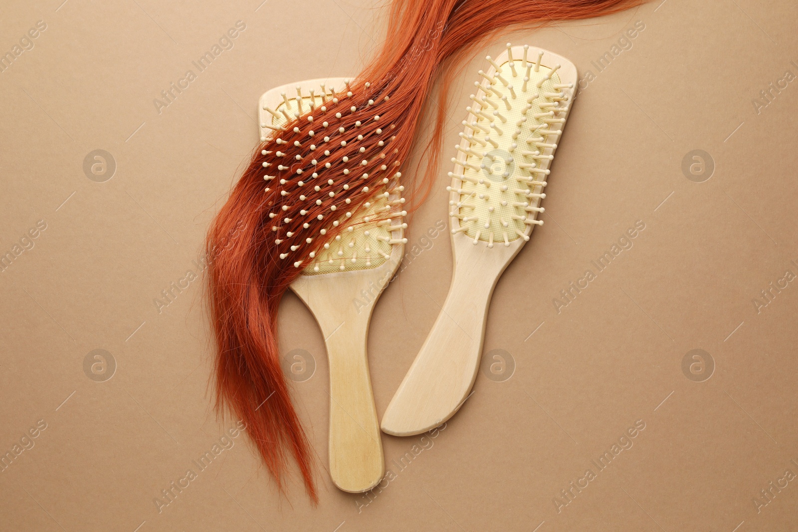 Photo of Wooden brushes and lock of hair on beige background, flat lay