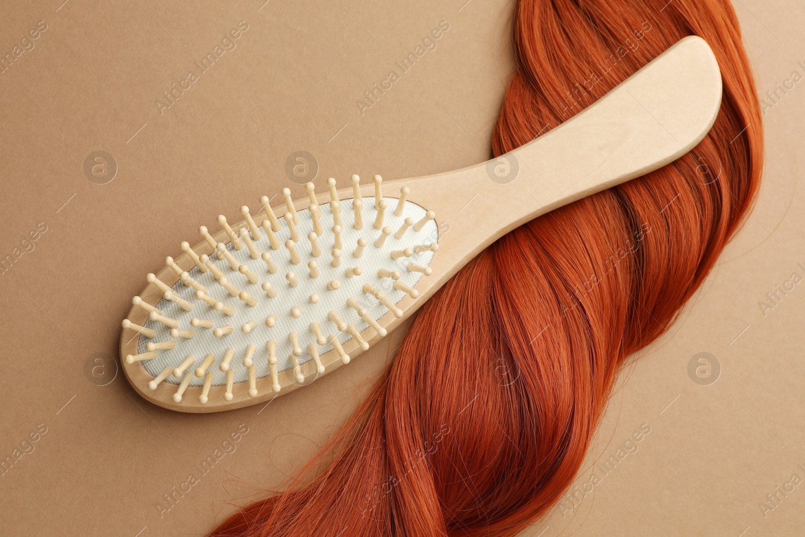 Photo of Wooden brush and lock of hair on beige background, top view