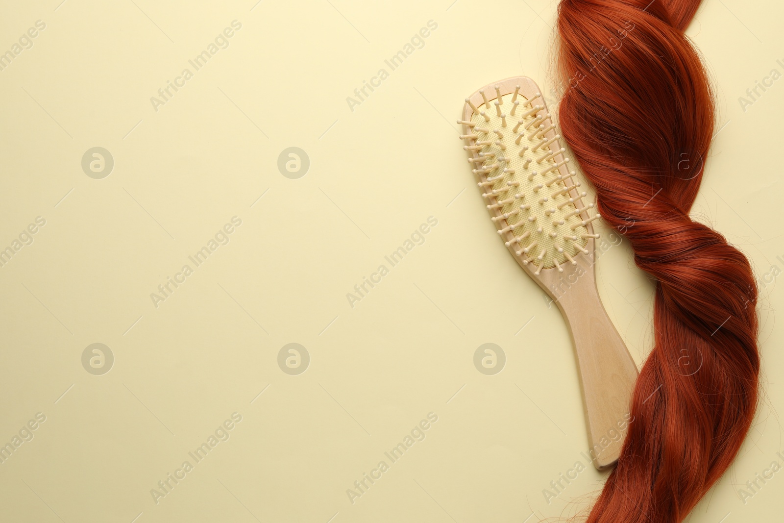 Photo of Wooden brush and lock of hair on beige background, top view. Space for text