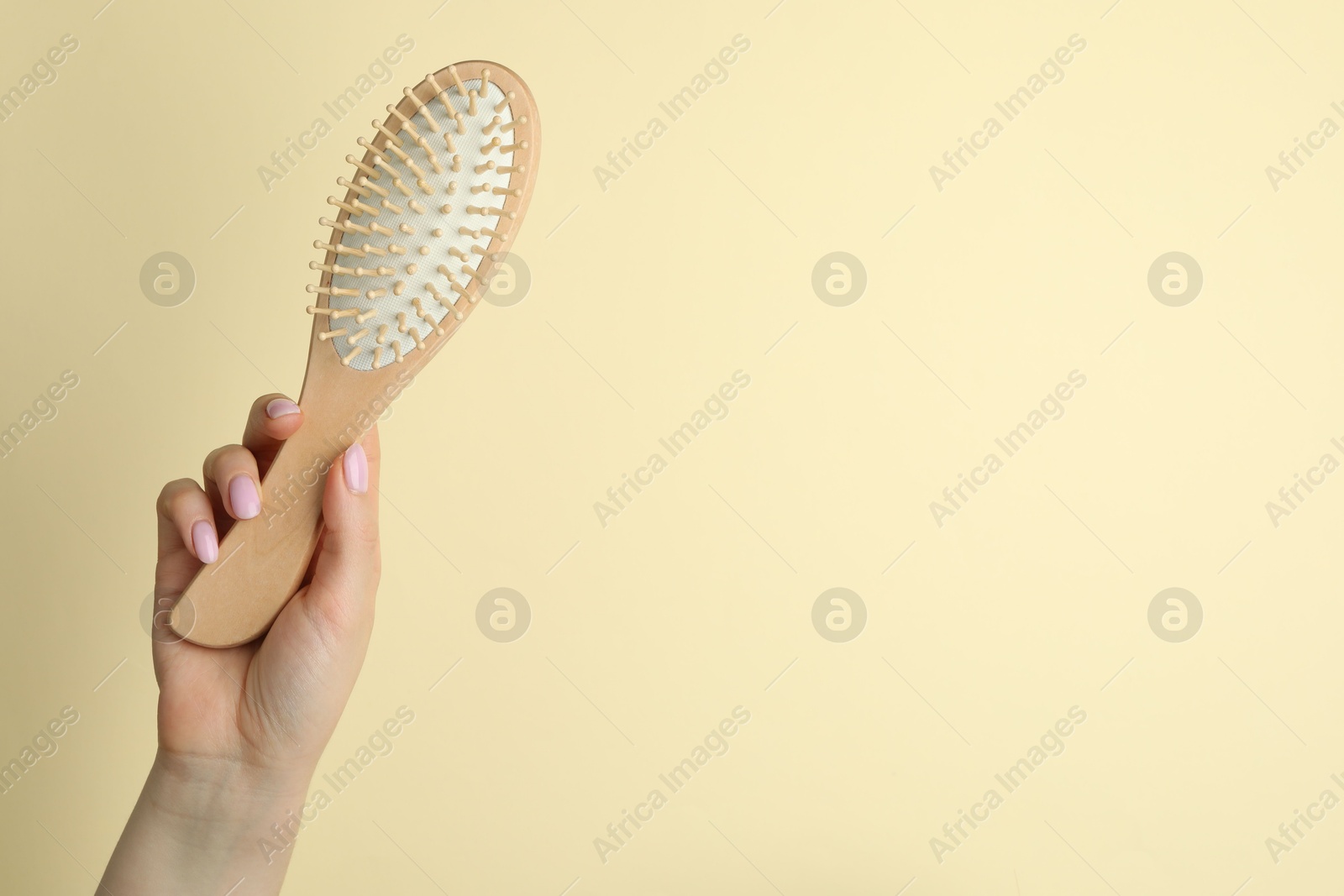 Photo of Woman with wooden brush on beige background, closeup. Space for text