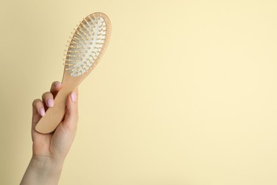 Photo of Woman with wooden brush on beige background, closeup. Space for text