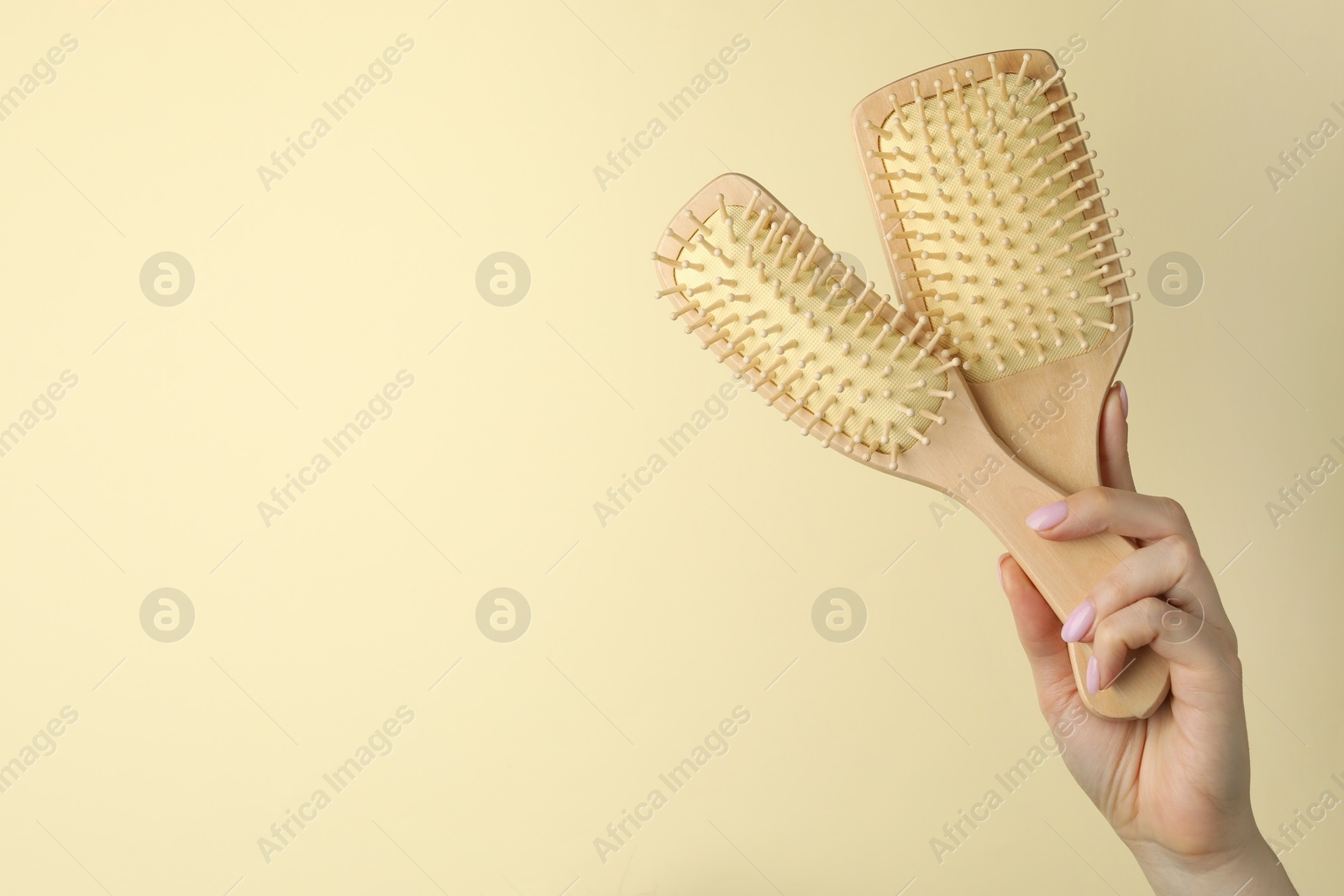 Photo of Woman with wooden brushes on beige background, closeup. Space for text