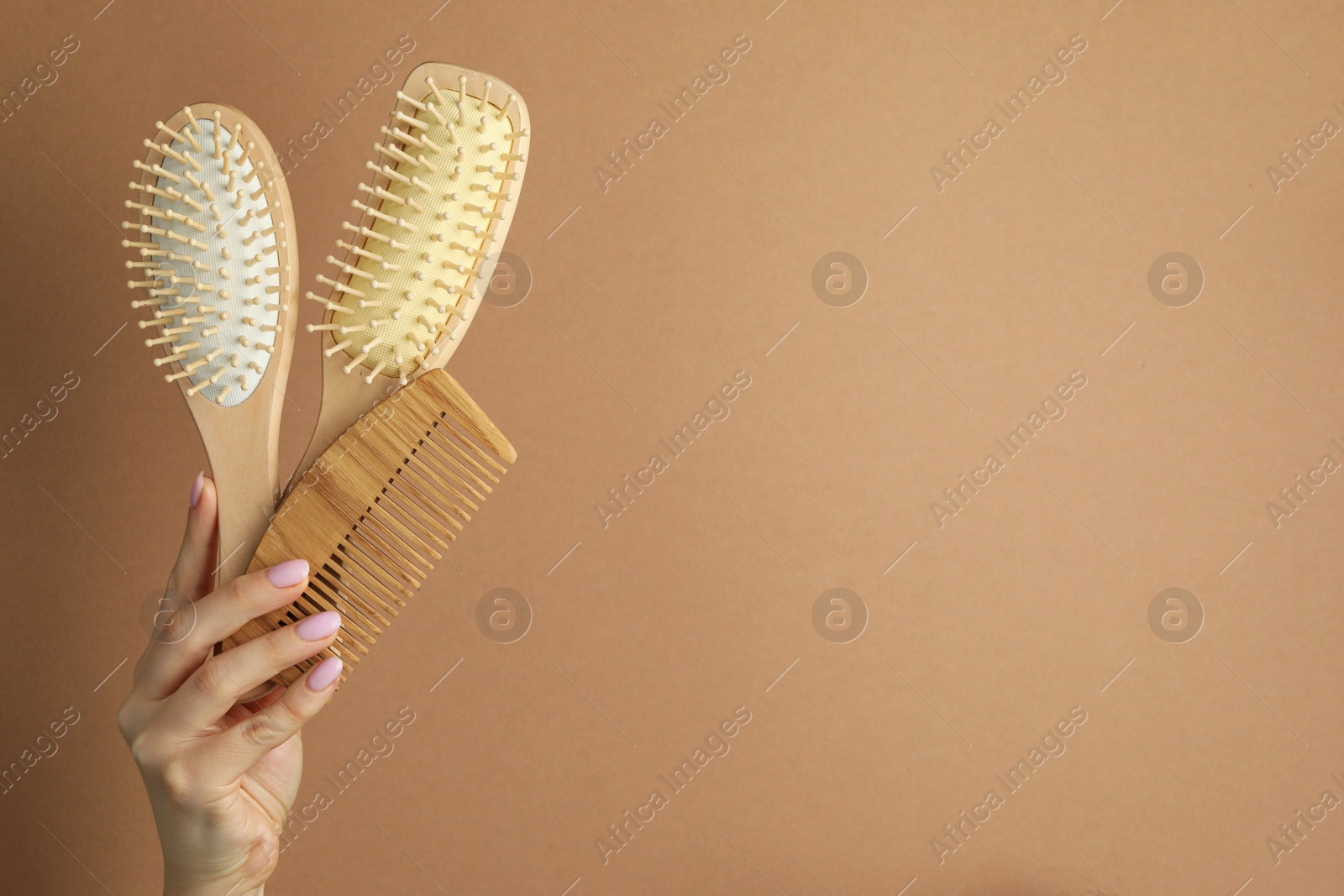 Photo of Woman with wooden brushes and comb on beige background, closeup. Space for text