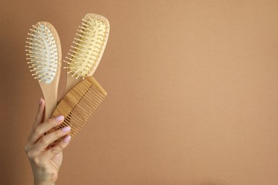 Photo of Woman with wooden brushes and comb on beige background, closeup. Space for text