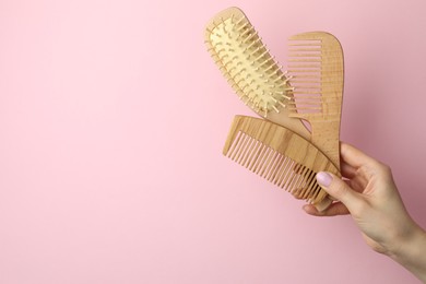 Photo of Woman with wooden brush and combs on pink background, closeup. Space for text