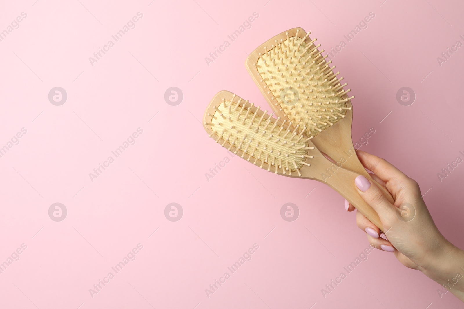 Photo of Woman with wooden brushes on pink background, closeup. Space for text