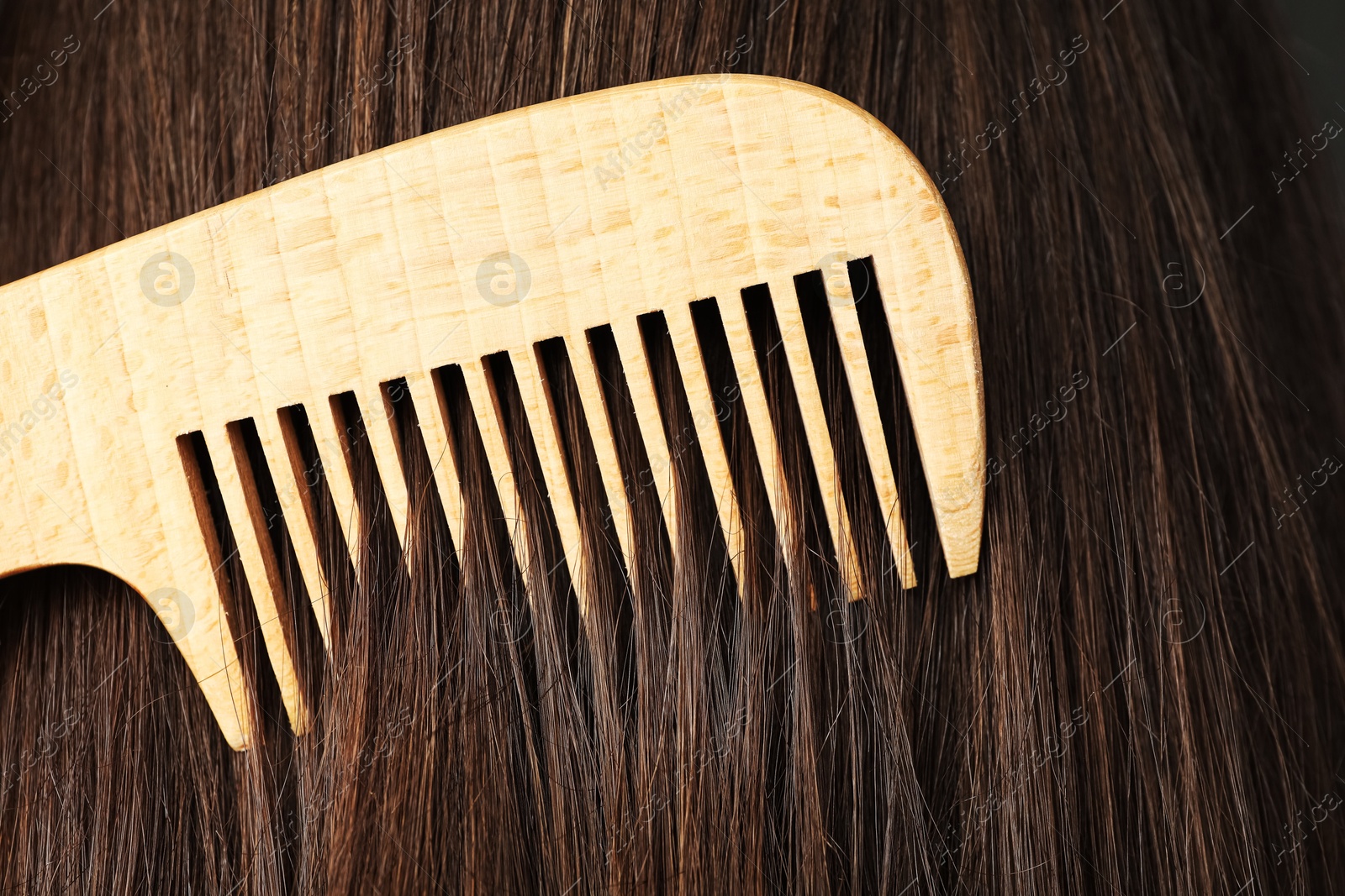 Photo of Brushing hair with wooden comb, closeup view