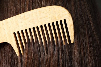 Photo of Brushing hair with wooden comb, closeup view