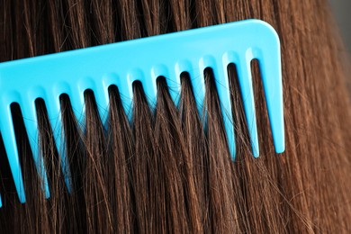 Photo of Brushing hair with plastic comb, closeup view