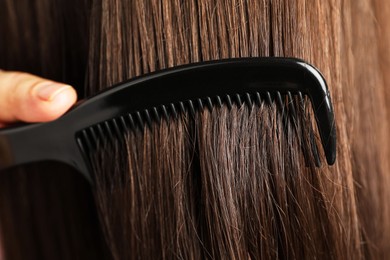 Photo of Woman brushing hair with plastic comb, closeup