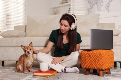 Photo of Young woman with her cute dog working on laptop at home