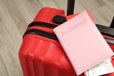 Photo of Passport with ticket and red suitcase on floor, closeup