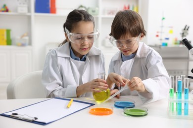 Photo of Children doing chemical experiment at desk indoors