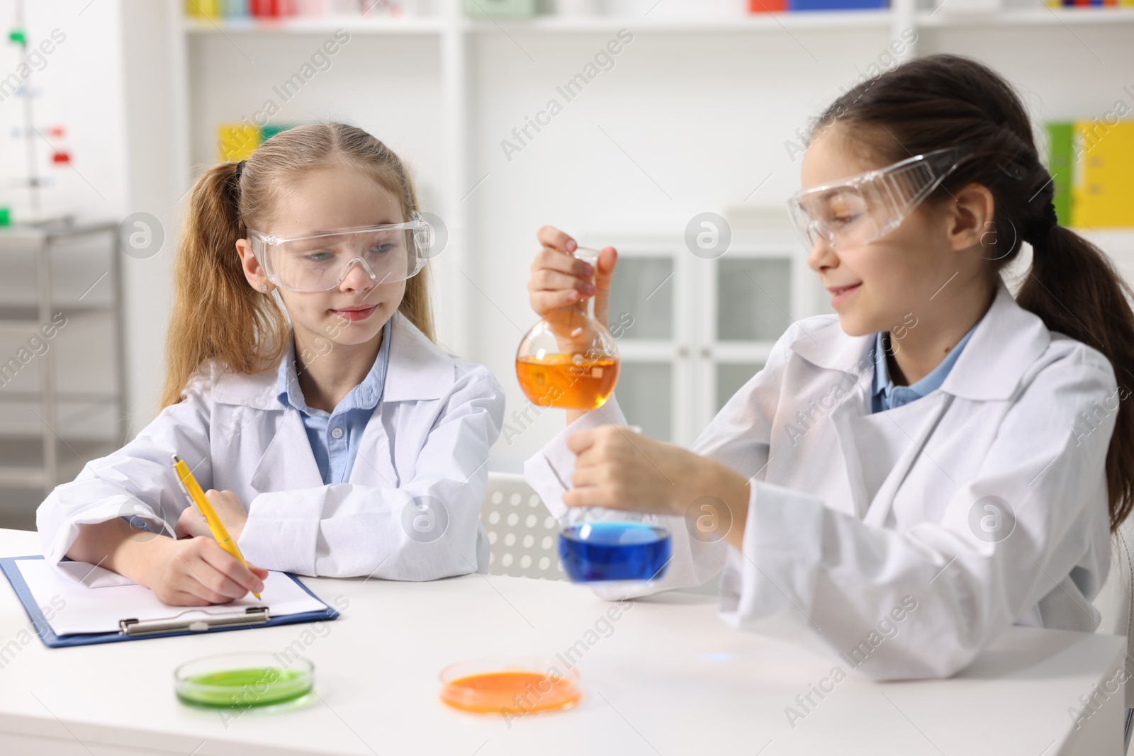 Photo of Children doing chemical experiment at desk indoors