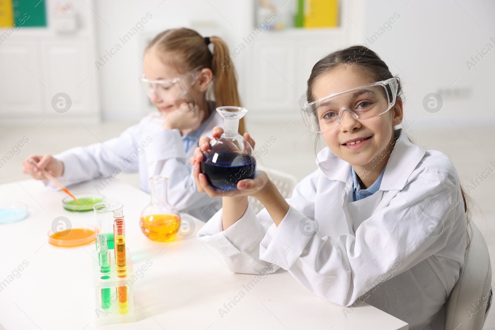 Photo of Children doing chemical experiment at desk indoors, selective focus