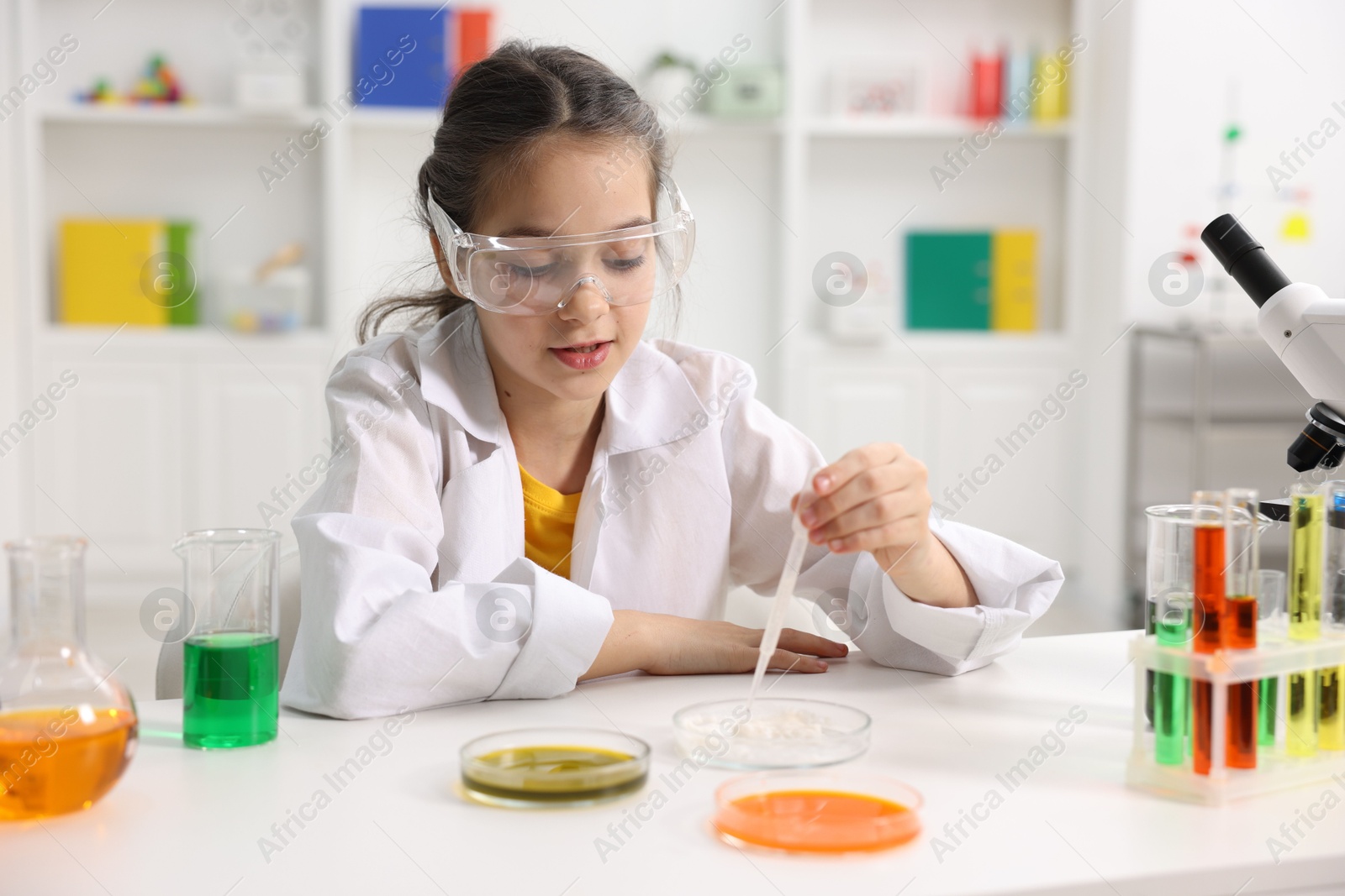 Photo of Little girl doing chemical experiment at desk indoors