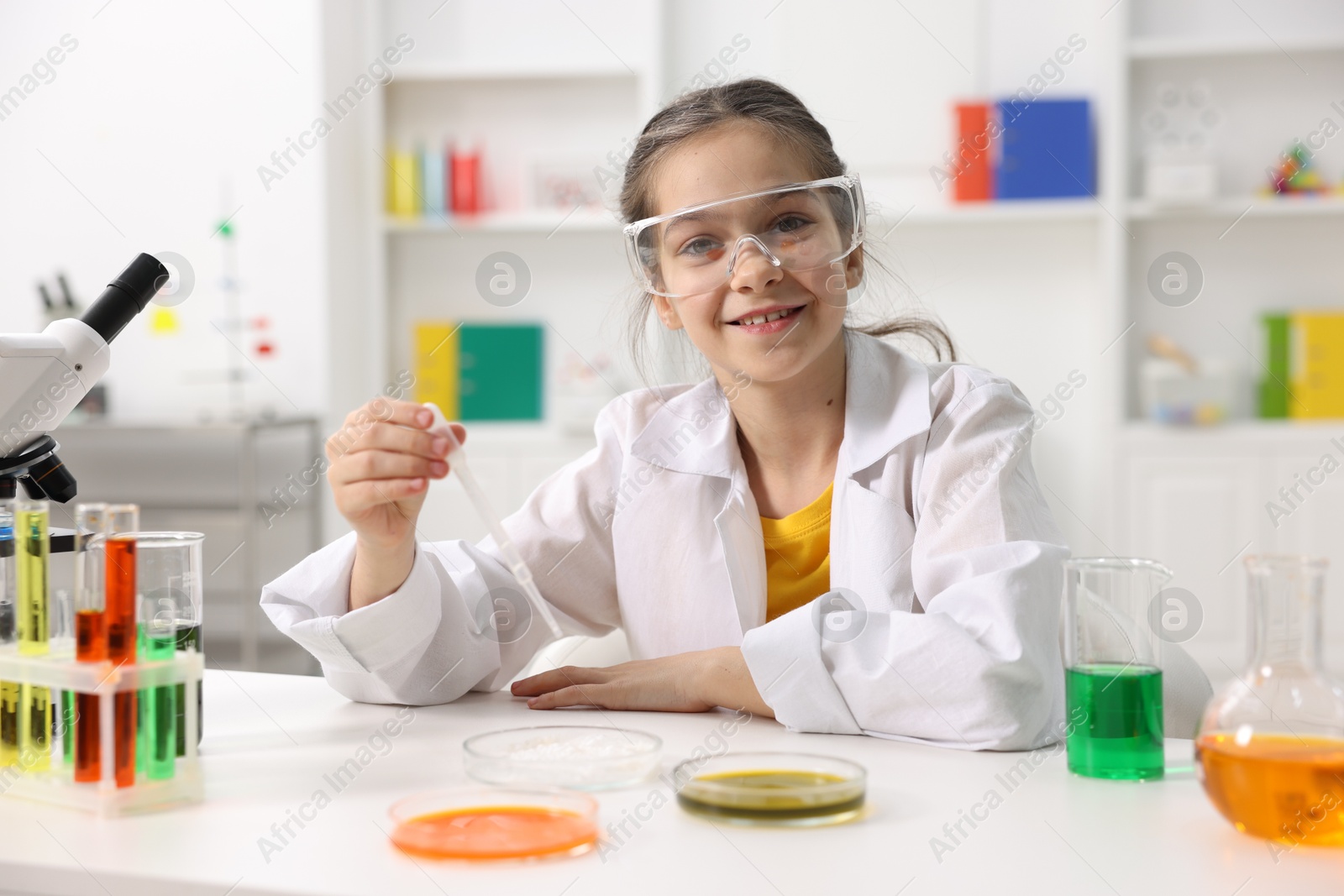 Photo of Little girl doing chemical experiment at desk indoors