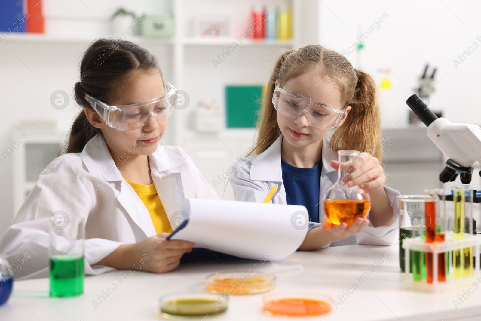 Photo of Children doing chemical experiment at desk indoors