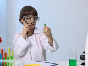 Photo of Little boy doing chemical experiment at desk indoors