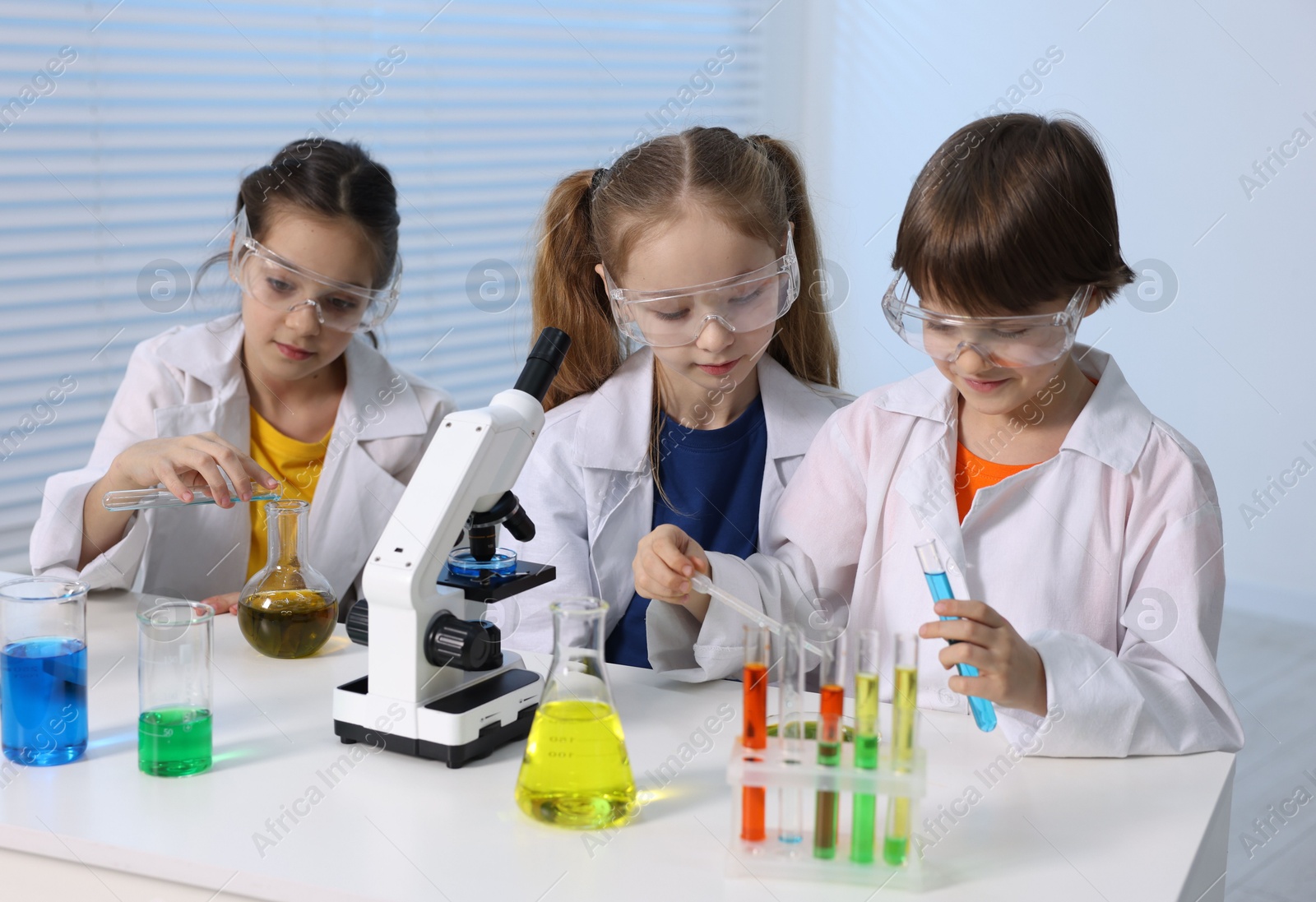 Photo of Children doing chemical experiment at desk indoors