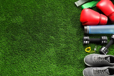 Photo of Different sports equipment on artificial grass, flat lay. Space for text