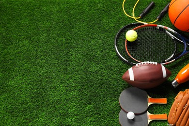 Photo of Different sports equipment on artificial grass, flat lay. Space for text