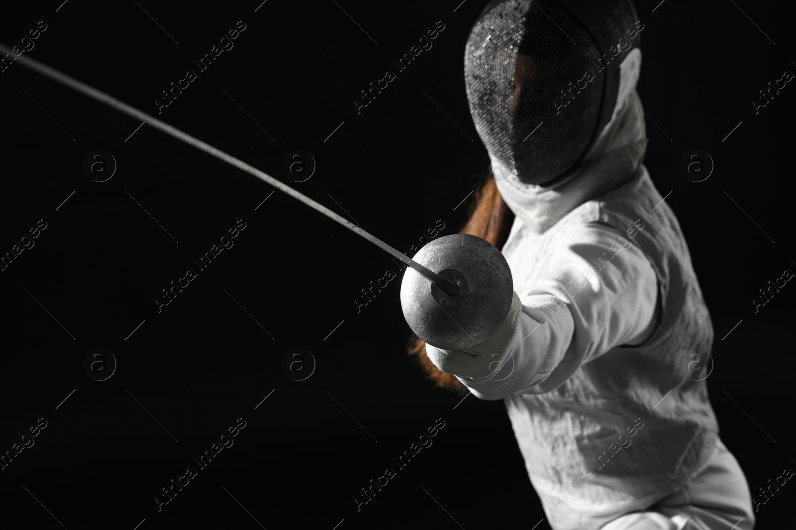 Photo of Fencer with epee practicing on black background, selective focus