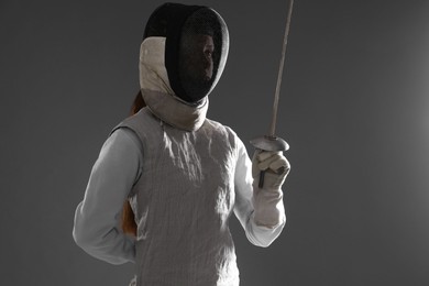 Photo of Fencer with epee on gray background. Combat sport