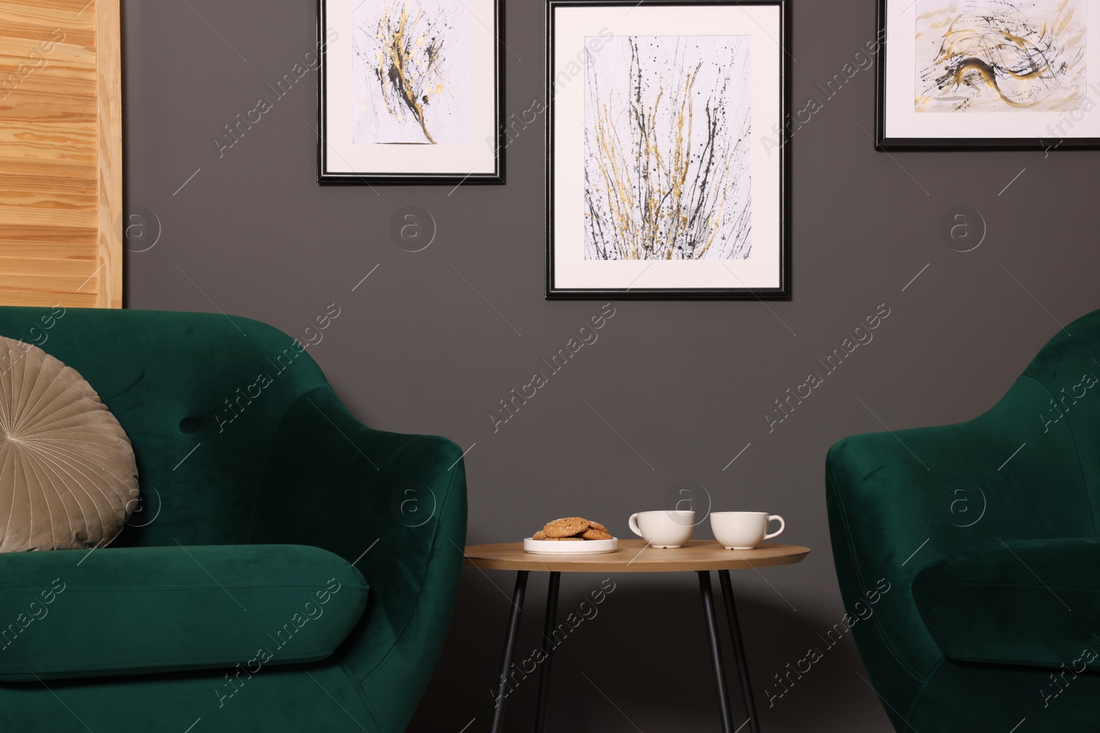 Photo of Coffee table with drinks and cookies between armchairs indoors