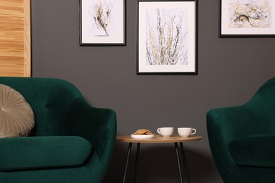 Photo of Coffee table with drinks and cookies between armchairs indoors