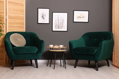 Photo of Nesting tables with coffee and cookies between armchairs indoors. Interior design