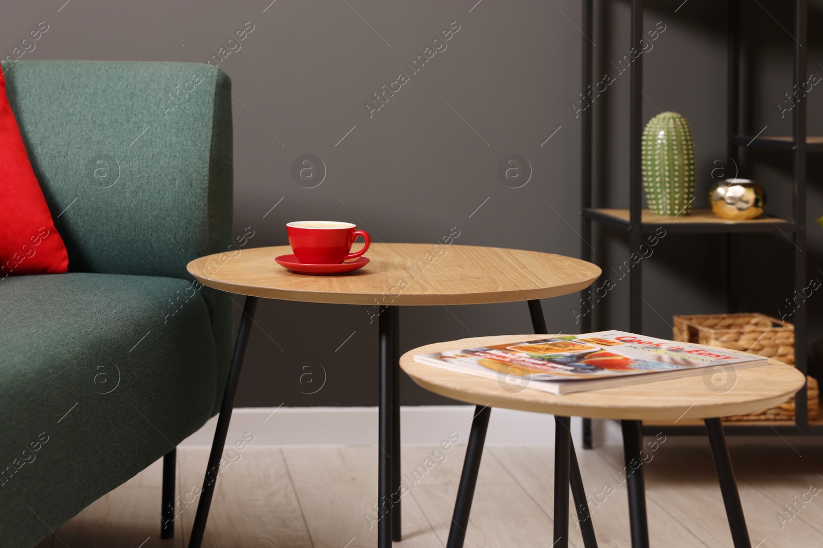 Photo of Nesting tables with coffee and magazine near sofa indoors. Interior design